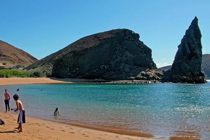 Personas relajándose y nadando en la playa cerca de la Roca Pinnacle en la Isla Bartolomé.
